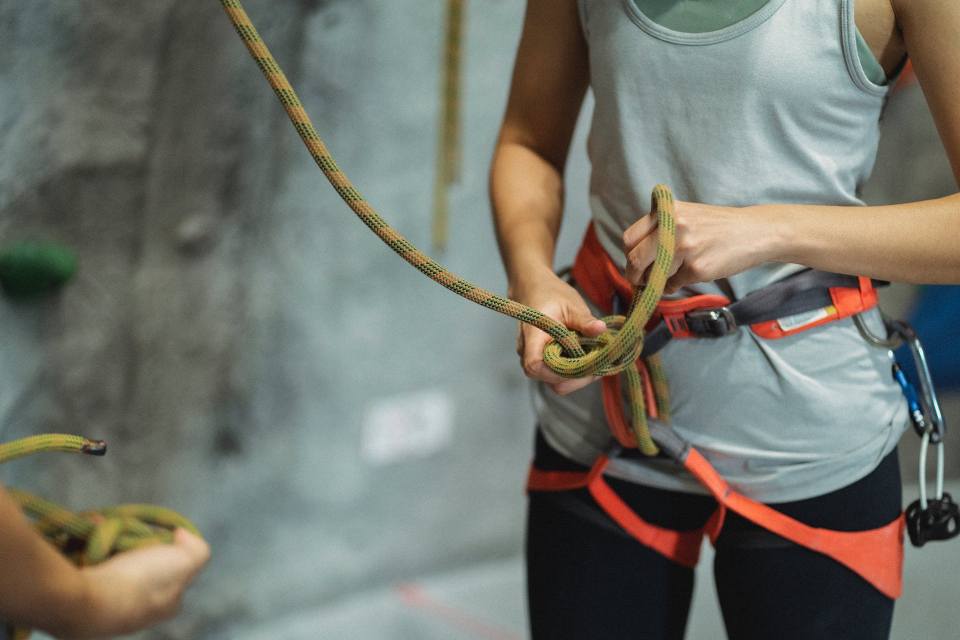 2. Alpinismul utilitar echipamentul necesar - femeie care este legata cu hamuri pentru escaladare